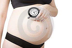 4 month pregnant woman on sport underwear holding alarm clock