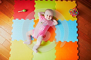 4 months old baby girl lying on colorful play mat