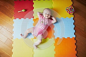 4 months old baby girl lying on colorful play mat