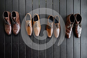 4 pairs of menâ€™s brown shoes on the black wooden floor