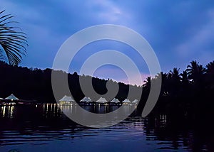 4 rivers tented jungle ecotourism hotel coming into view around a bend in the Kong River at twilight