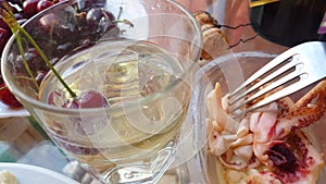 4 to the video, eating seafood with a fork on the background of a glass of white sparkling wine, close-up