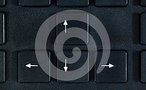 4 white arrows on the black buttons of black keyboard close up