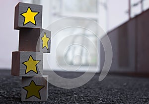 4 wooden cubes with a pattern of a yellow star standing on top of each other on asphalt