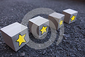 4 wooden cubes with a pattern of a yellow star standing on top of each other on asphalt