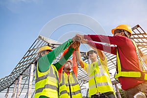 4 Workers, Architect and Engineer construction workers join hands while working at outdoors construction site. Teamwork Concept