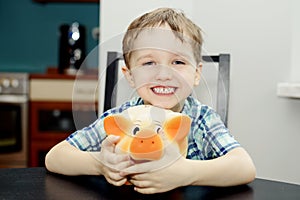 4 year old boy smiling while holding a piggy bank