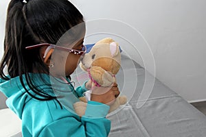 4-year-old brunette Latina girl with glasses represents mistreatment and physical abuse in her teddy bear with bandages on her hea