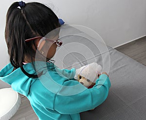 4-year-old brunette Latina girl with glasses represents mistreatment and physical abuse in her teddy bear with bandages on her hea