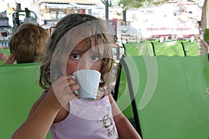 A 4 year old girl drinks a decaf in a Toroni bar in Greece