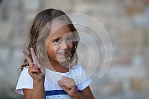 4 year old girl smiling make a sign of victory