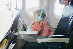 4 year old girl using tablet while travelling by plane