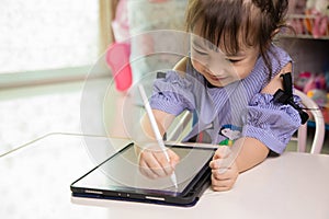 4-year old girl writting her tablet at home