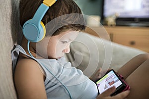 4 years boy in headphones watching videos at smartphone