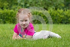 A 4 years old girl playing with a cuddly toy on the grass in a park