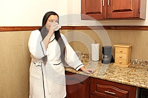 40-year-old Latina woman in a bathrobe drinks a cup of coffee in her kitchen to avoid diabetes, parkinson\'s and depression