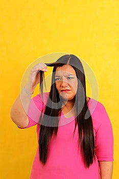 40-year-old Latina woman with long hair suffers from having it mistreated, observes her damaged split ends that need treatment