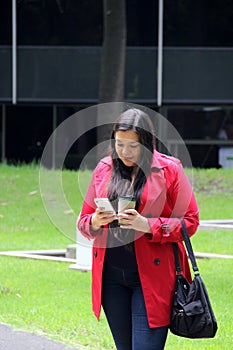 40-year-old Latina woman walks while drinking coffee and using cell to work, make video calls, send messages and make payments