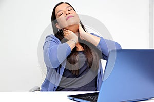 40-year-old woman suffers from back, neck and head pain due to stress and burnout while working in her office with her laptop