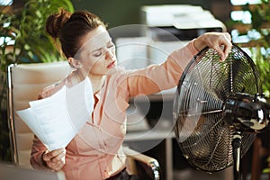 40 years old woman employee in green office suffer from heat