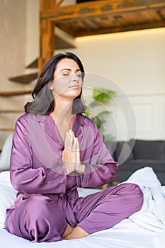 40 years old woman meditating on bed. Mettal health and digital detox concept.