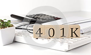 401 K written on a wooden cube on keyboard with office tools