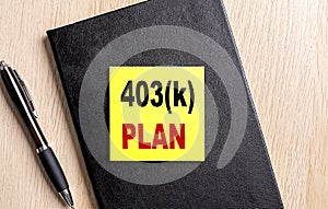 403K PLAN text on a sticky on black notebook with pen