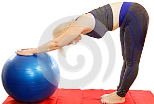 A 48-year-old woman performs an exercise from a Pilates course leaning towards fitball