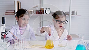 4K, 2 Cute girls taking on roles of little scientists having fun experimenting and mixing colors in the school lab wants to have