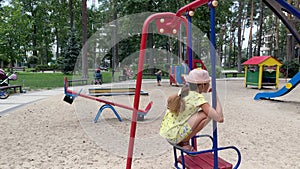 4k 2 sisters swinging on a swing on a playground.