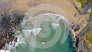 4K aerial of breaking waves on beach and rugged coastline