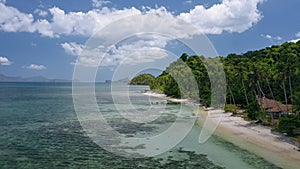 4k Aerial drone fly along exotic tropical beach with banca boat in shallow water and coconut palm trees in El Nido