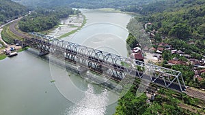 4k aerial drone view of the Serayu River railway bridge, Indonesia with a river, mountains and trees in the background