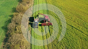 4K Aerial Elevated View Of Combine Harvester And Tractor Working Together In Field. Harvesting Of Oilseed In Spring