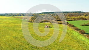 4K Aerial Elevated View Of Combine Harvester And Tractor Working Together In Field. Harvesting Of Oilseed In Spring