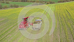 4K Aerial Elevated View Of Combine Harvester And Tractor Working Together In Field. Harvesting Of Oilseed In Spring