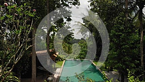 4K aerial flying video of infinity swimming pool at luxury villa in the jungle. Bali island.