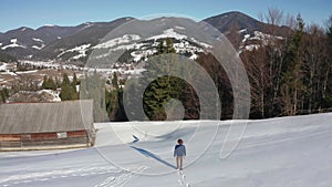 4k aerial top view Young adult man in denim jacket hat walking running on snow mountain at winter