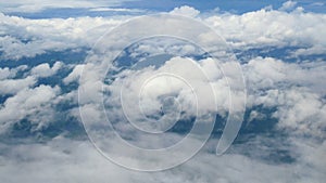 4K. aerial view through an airplane window. beautiful white clouds in blue sky background. traveling by air.