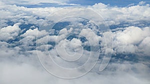 4K. aerial view through an airplane window. beautiful white clouds in blue sky background. traveling by air.