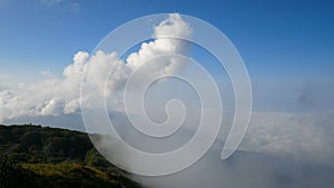 4K. aerial view of foggy mountains in the mist with blue sky and white cloud with adventurous hiking climbers, speed up.