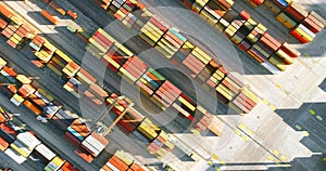 4K aerial view of harbor crane moving diagonally above colorful containers in the port