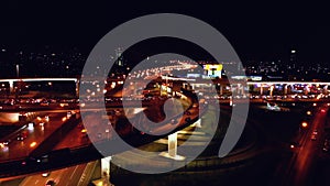 4K. Aerial view of highway road interchange with busy urban traffic speeding on the road at night. Junction network of