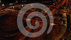 4K. Aerial view of highway road interchange with busy urban traffic speeding on the road at night. Junction network of