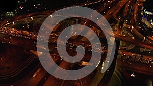 4K. Aerial view of highway road interchange with busy urban traffic speeding on the road at night. Junction network of