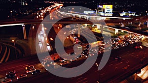 4K. Aerial view of highway road interchange with busy urban traffic speeding on the road at night. Junction network of