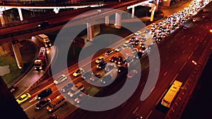 4K. Aerial view of highway road interchange with busy urban traffic speeding on the road at night. Junction network of