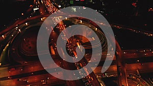 4K. Aerial view of highway road interchange with busy urban traffic speeding on the road at night. Junction network of