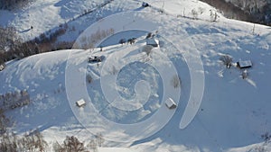 4K Aerial view of Sirnea village from Rucar-Bran Pass in Romania during a winter morning at the bottom of Piatra-Craiului Mountain