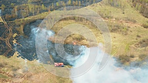 4K Aerial View Spring Dry Grass Burns During Drought Hot Weather. Bush Fire And Smoke. Fire Engine, Fire Truck On